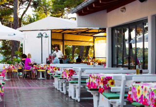 Außenrestaurant im Baia Holiday Poljana in Kroatien mit bunten Tischdecken und Gästen beim Essen.