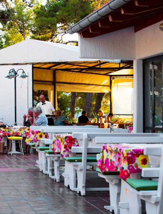 Restaurant en plein air à Baia Holiday Poljana, Croatie, avec nappes colorées et clients attablés ensemble.