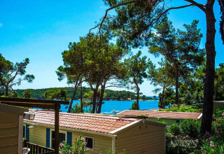 Parque vacacional en Primorje-Gorski Kotar, Croacia, con casas móviles entre pinos y vista al mar.