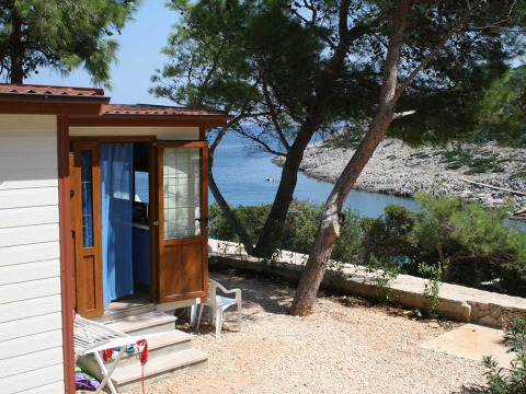 Baia Lux lodge bij Baia Holiday Poljana in Kroatië, met uitzicht op zee, bomen en een rotsachtige kust.