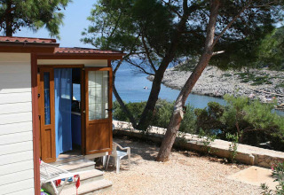 Baia Lux lodge bij Baia Holiday Poljana in Kroatië, met uitzicht op zee, bomen en een rotsachtige kust.