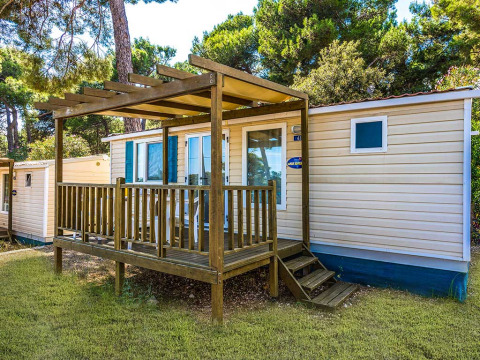 Mobil-home avec terrasse en bois à Baia Superior, Baia Holiday Poljana, Croatie, entouré d’arbres.