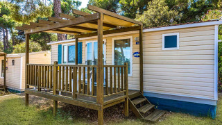 Casa mobile con veranda in legno al Baia Superior, Baia Holiday Poljana in Croazia, circondata da pini.