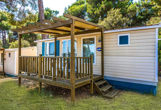 Mobil-home avec terrasse en bois à Baia Superior, Baia Holiday Poljana, Croatie, entouré d’arbres.