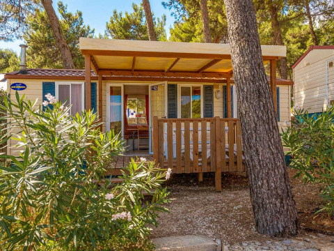 Véranda en bois devant le lodge Blu Romantic à Baia Holiday Poljana, Croatie, entourée de pins verts.