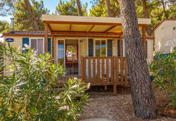 Veranda in legno davanti al lodge Blu Romantic al Baia Holiday Poljana, Croazia, circondata da pini.