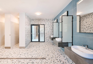 Moderne badkamer met terrazzovloer, spiegels, lavabo’s en douches in Aminess Style Camping Avalona Resort.