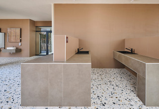 Baño comunitario moderno con suelo de terrazo y paredes beige en Aminess Style Camping Avalona Resort, Croacia.