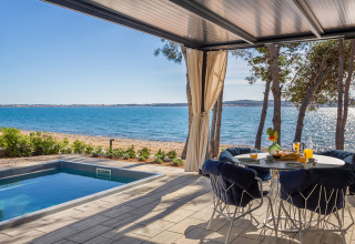 Terraszicht bij Amber Sea Luxury Holiday Home Pool op Aminess Style Camping Avalona Resort in Kroatië met zee en zwembad.