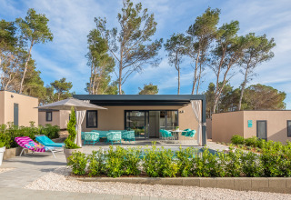 Casa de vacaciones moderna en el Aminess Style Camping Avalona Resort en Zadar, Croacia, rodeada de pinos y muebles exteriores.