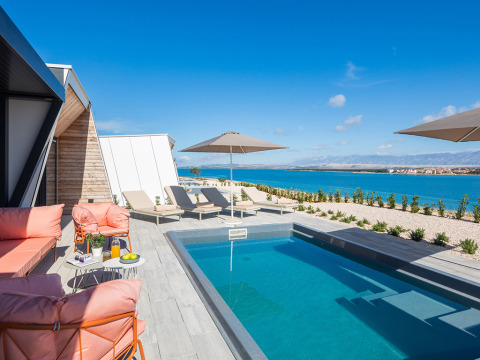 Moderne Poolterrasse mit Sonnenliegen, Sonnenschirmen und Meerblick im Aminess Style Camping Avalona Resort, Kroatien.