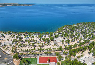 Aerial view of Aminess Style Camping Avalona Resort in Croatia, featuring sea, trees, and a sports court.