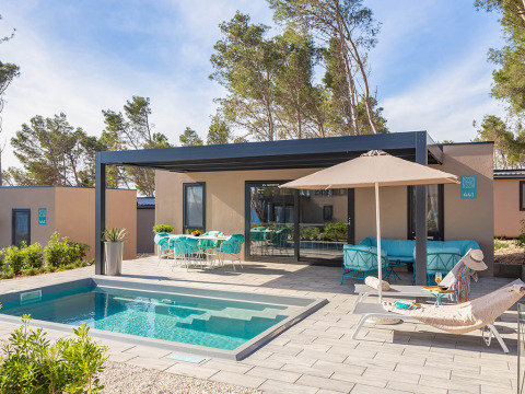 Casa de vacaciones de lujo con piscina privada, tumbonas, sombrilla y comedor exterior junto a la piscina.