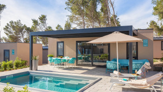 Luxe chalet met privézwembad, comfortabele lounge, ligzetels, parasol en buiteneethoek op terras.