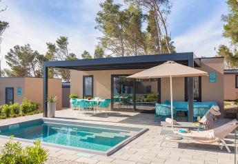 Casa vacanza di lusso con piscina privata, lettini prendisole, ombrellone e area pranzo all'aperto.
