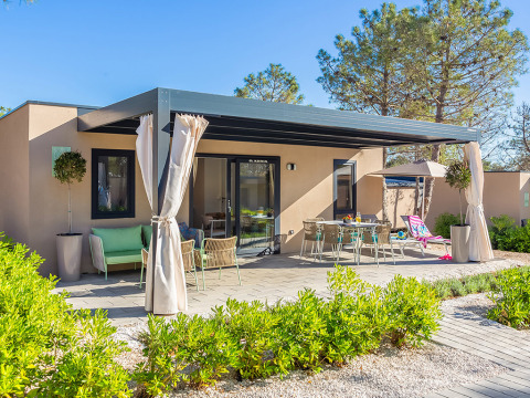 Vista esterna del chalet Family Premium Holiday Home con terrazza, tavolo da pranzo e piante verdi.