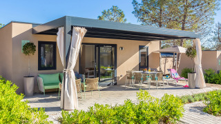 Vista esterna del chalet Family Premium Holiday Home con terrazza, tavolo da pranzo e piante verdi.