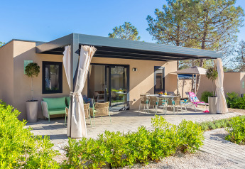 Vista esterna del chalet Family Premium Holiday Home con terrazza, tavolo da pranzo e piante verdi.