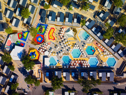 Aerial view of Aminess Style Camping Atea Resort, showing colorful pools, umbrellas, and vacation cottages.