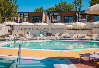 Outdoor swimming pool with sun loungers, umbrellas and modern cabins at Aminess Style Camping Atea Resort in Croatia.