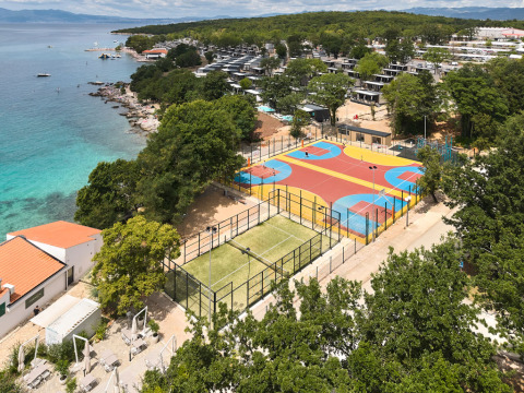 Ferienpark mit bunten Sportplätzen am türkisblauen Meer im Aminess Style Camping Atea Resort, Kroatien.