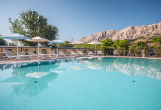 Piscina al aire libre con tumbonas y sombrillas en Valamar Camping Baška, Primorje-Gorski Kotar, Croacia.