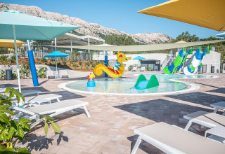 Kindvriendelijk zwembad met ligbedden, waterspeelgoed en glijbanen bij Valamar Camping Baška, Kroatië.