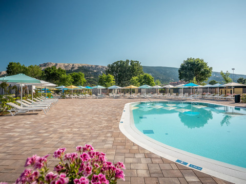 Piscina all'aperto con lettini e ombrelloni presso Valamar Camping Baška, parco vacanze in Croazia.