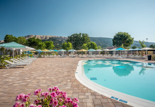 Piscina al aire libre con tumbonas y sombrillas en Valamar Camping Baška, un parque vacacional en Croacia.