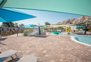 Udendørs swimmingpoolområde i Valamar Camping Baška med liggestole, parasoller og bjerge i baggrunden.