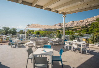 Outdoor terrace seating at Valamar Camping Baška with scenic mountain views in Primorje-Gorski Kotar, Croatia.
