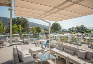 Udendørs terrasse med komfortable sofaer og udsigt over Valamar Camping Baška i Kroatien, omgivet af bjerge.