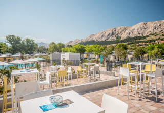 Udendørs caféområde med udsigt over bjerge og swimmingpool i Valamar Camping Baška, Primorje-Gorski Kotar, Kroatien.