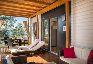 Overdækket terrasse med liggestole, spisebord og loungemøbler på en feriebolig i Kroatien ved havet.