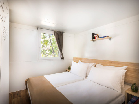 Bright bedroom with twin beds, wooden floor, pillows, and a window at Aminess Style Camping Atea Resort, Croatia.