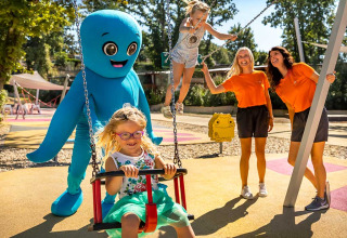 Niños se divierten en un parque infantil con una mascota azul en Aminess Style Camping Atea Resort, Croacia.