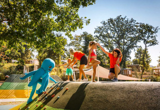 Niños y adultos se divierten en un parque infantil en Aminess Style Camping Atea Resort en Croacia en un día soleado.
