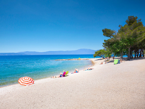 Strand mit Sonnenschirmen am Aminess Style Camping Atea Resort, Primorje-Gorski Kotar, Kroatien.