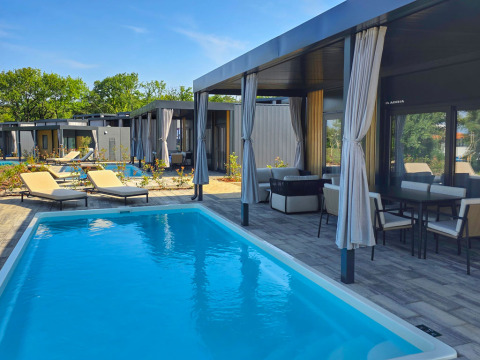 Udendørs poolområde med moderne ferieboliger, liggestole og overdækkede terrasser på Aminess Style Camping Atea Resort.