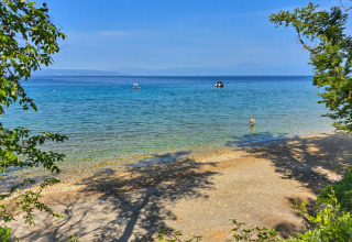 View of the beach with clear blue water at Aminess Style Camping Atea Resort in Primorje-Gorski Kotar, Croatia.