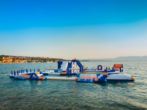 Parque acuático inflable en Aminess Style Camping Atea Resort en Croacia con niños jugando en el mar.