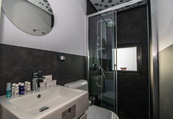 Moderne badeværelse i et chalet med glasbrusekabine, sort-hvide vægge, vask og toilet.