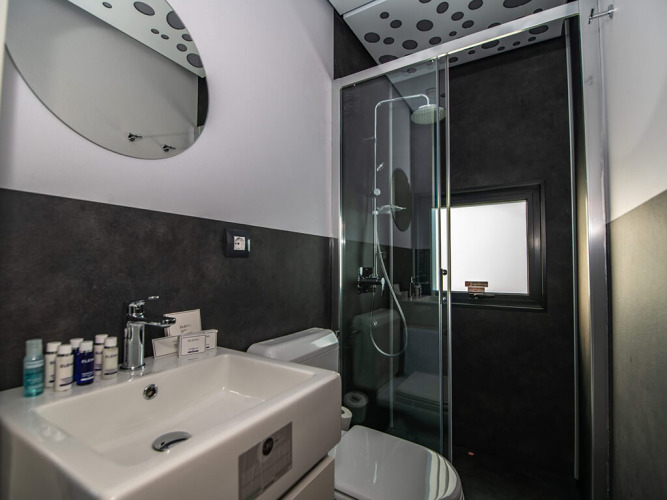 Chaletbadkamer met glazen douche, wastafel, toilet en strak interieur met donkere accenten.