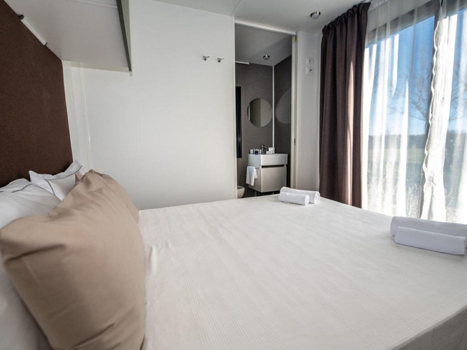 Moderne soveværelse i Camping Home Green på Camping Arena Grand Kažela i Kroatien med stor seng og lysindfald.