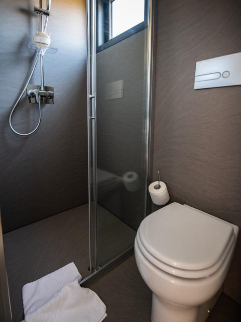 Moderne campingbadkamer met douche, toilet en raam bij Camping Home Green, Arena Grand Kažela, Kroatië.