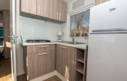 Cocina moderna de chalet con armarios de madera, estufa de gas, cafetera, fregadero y frigorífico grande.