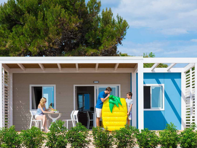 Gezin ontspant voor een chalet op Camping Home Next, Camping Arena Grand Kažela, Kroatië.