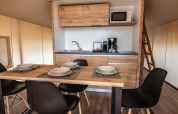 Innenansicht eines Safari-Zeltes im Camping Arena Stoja mit Esstisch, Küche und Holzleiter zum Loft.