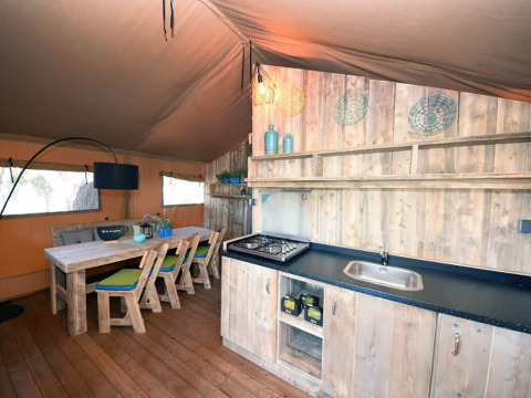 Interno di una tenda glamping con angolo cottura e tavolo da pranzo al Camping Arena Stoja in Croazia.