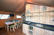 Interior de una tienda de glamping con cocina y comedor de madera en Camping Arena Stoja, Croacia.